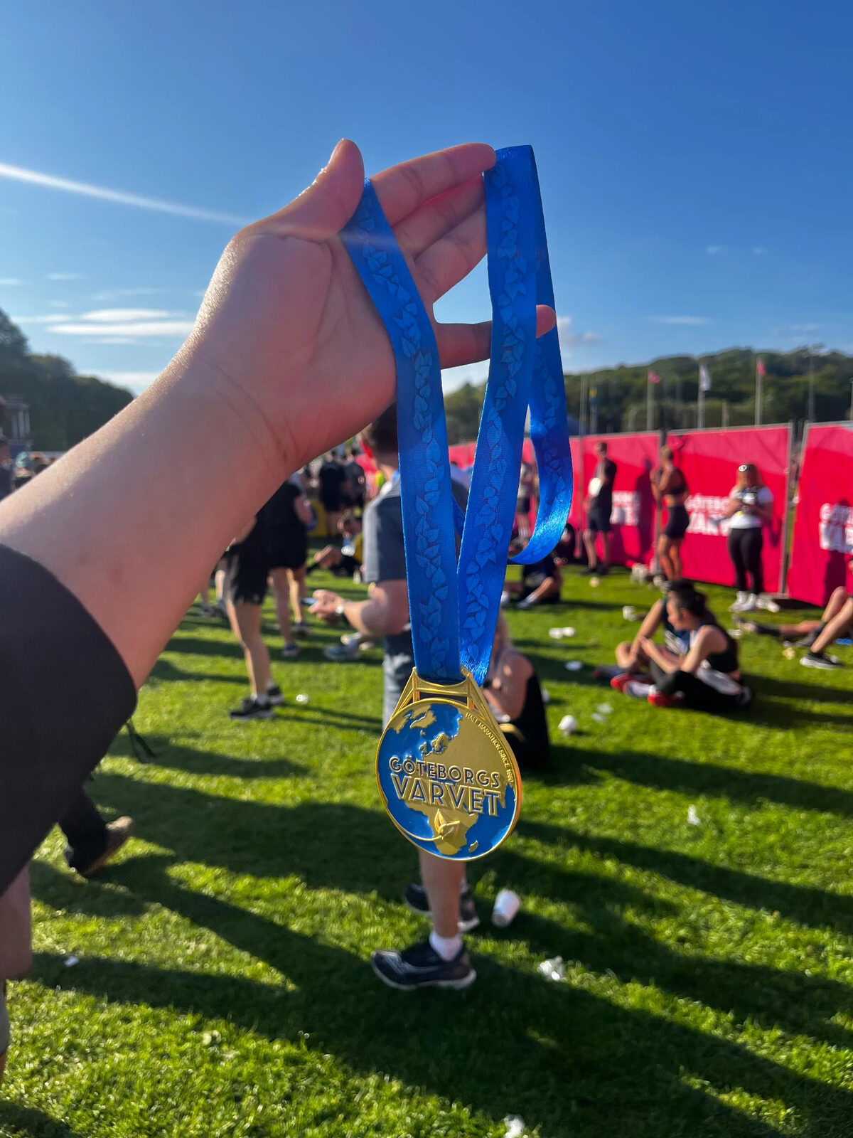 Holding the Göteborgsvarvet finisher medal on the grass after the race